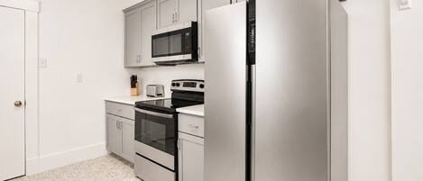 Una cocina moderna con electrodomésticos de acero inoxidable, microondas, horno y refrigerador.