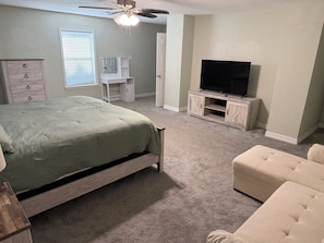 Un dormitorio con cama, televisión, escritorio y silla.