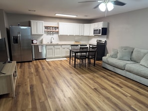 Una cocina moderna con armarios blancos, microondas integrado y un comedor con mesa y sillas.