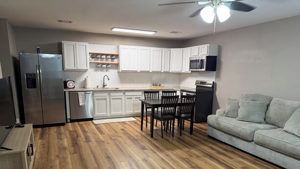 A modern kitchen with white cabinets, a built-in microwave, and a dining area with a wooden table and chairs. - A HomeAwayFromHome
just 2 miles from Kyle
Field. (College Station)