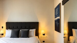 A hotel room with a large bed, two bedside lamps, a wall-mounted artwork, and a mirror. - Park Tower | Santa Elena Sur Area & U.S. Embassy (Nuevo Cuscatlan)