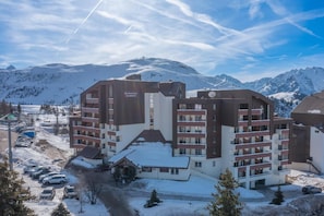 A multi-story hotel with a ski resort in the background. - Wifi, 100m from ski slopes, swimming pool, sauna, balcony, ski locker, 19m², Alpe d'Huez (L'Alpe d'Huez)