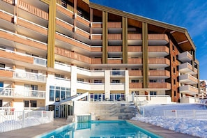 A multi-story hotel with balconies, a swimming pool, and a ski slope in the background. - Wifi, 100m from ski slopes, swimming pool, sauna, balcony, ski locker, 28-32m², Alpe d'Huez (L'Alpe d'Huez)