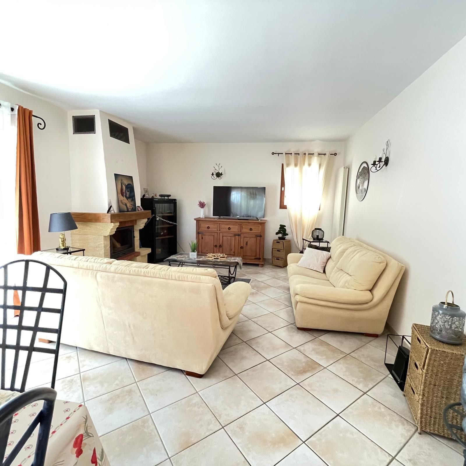 Una sala de estar con sofá, televisión, chimenea y un comedor con mesa y sillas.