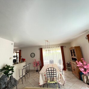 A dining area with a table, chairs, a clock, and a cabinet. - Caro's Villa in Blauzac (Blauzac)