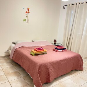 A bedroom with a bed, pillows, a bedside table with a lamp, and a wall decoration. - Caro's Villa in Blauzac (Blauzac)