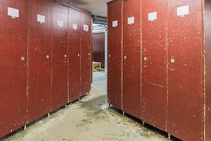 A row of red lockers with visible signs, a concrete floor, and a visible duct in the background. - Wifi, 100m from ski slopes, swimming pool, sauna, balcony, ski locker, 38m², Alpe d'Huez (L'Alpe d'Huez)