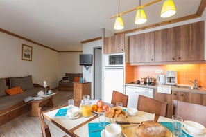 A compact living space with a kitchenette, dining area, and a sofa. - Wifi, 100m from ski slopes, swimming pool, sauna, balcony, ski locker, 38m², Alpe d'Huez (L'Alpe d'Huez)