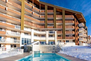 A multi-story hotel with balconies, a swimming pool, and a ski slope in the background. - Wifi, 100m from ski slopes, swimming pool, sauna, balcony, ski locker, 40m², Alpe d'Huez (L'Alpe d'Huez)