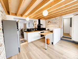 Eine moderne Küche mit Holzbalken, einem Kühlschrank und einem Spülbecken.