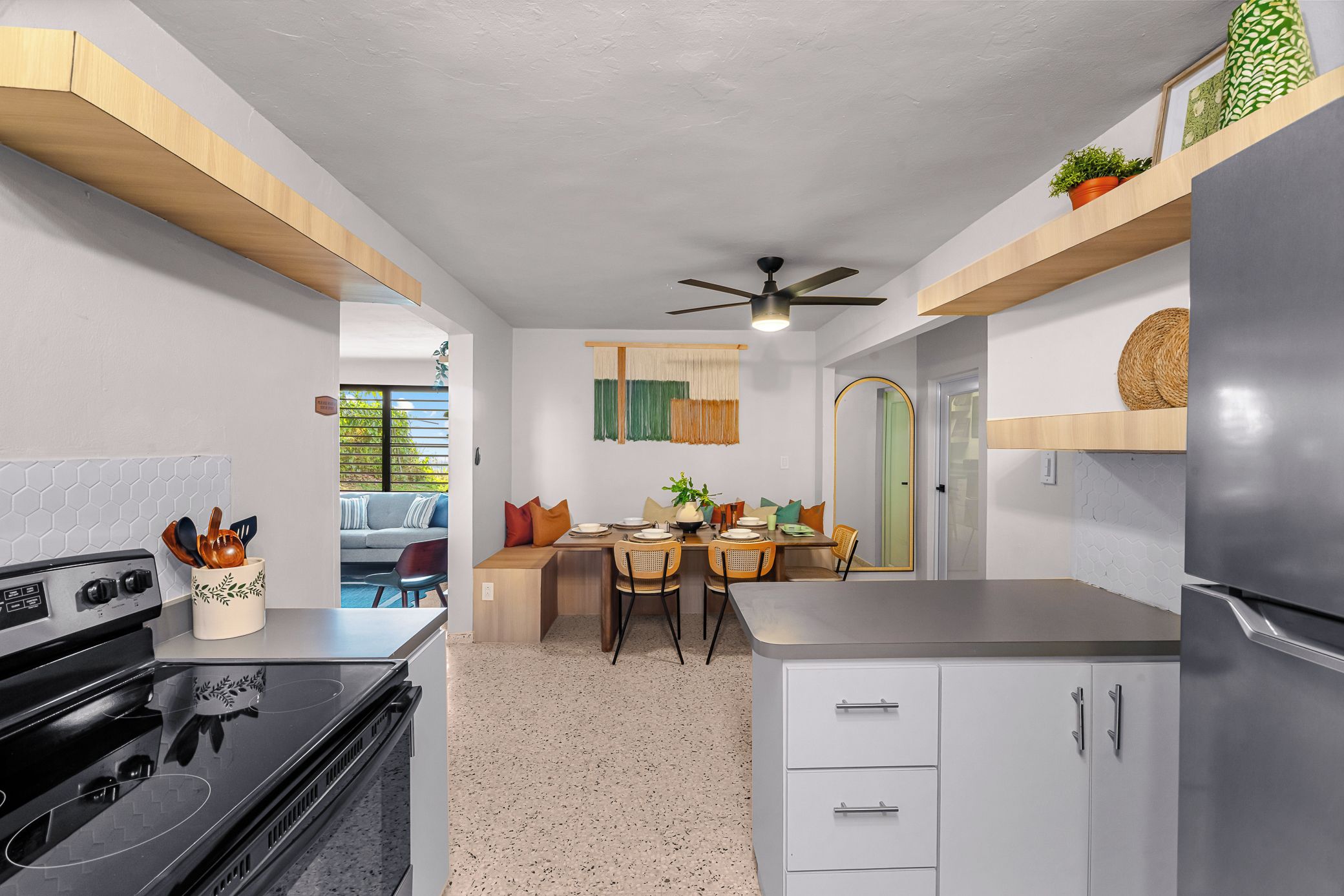 Una cocina moderna con estufa integrada, refrigerador y comedor con mesa y sillas.