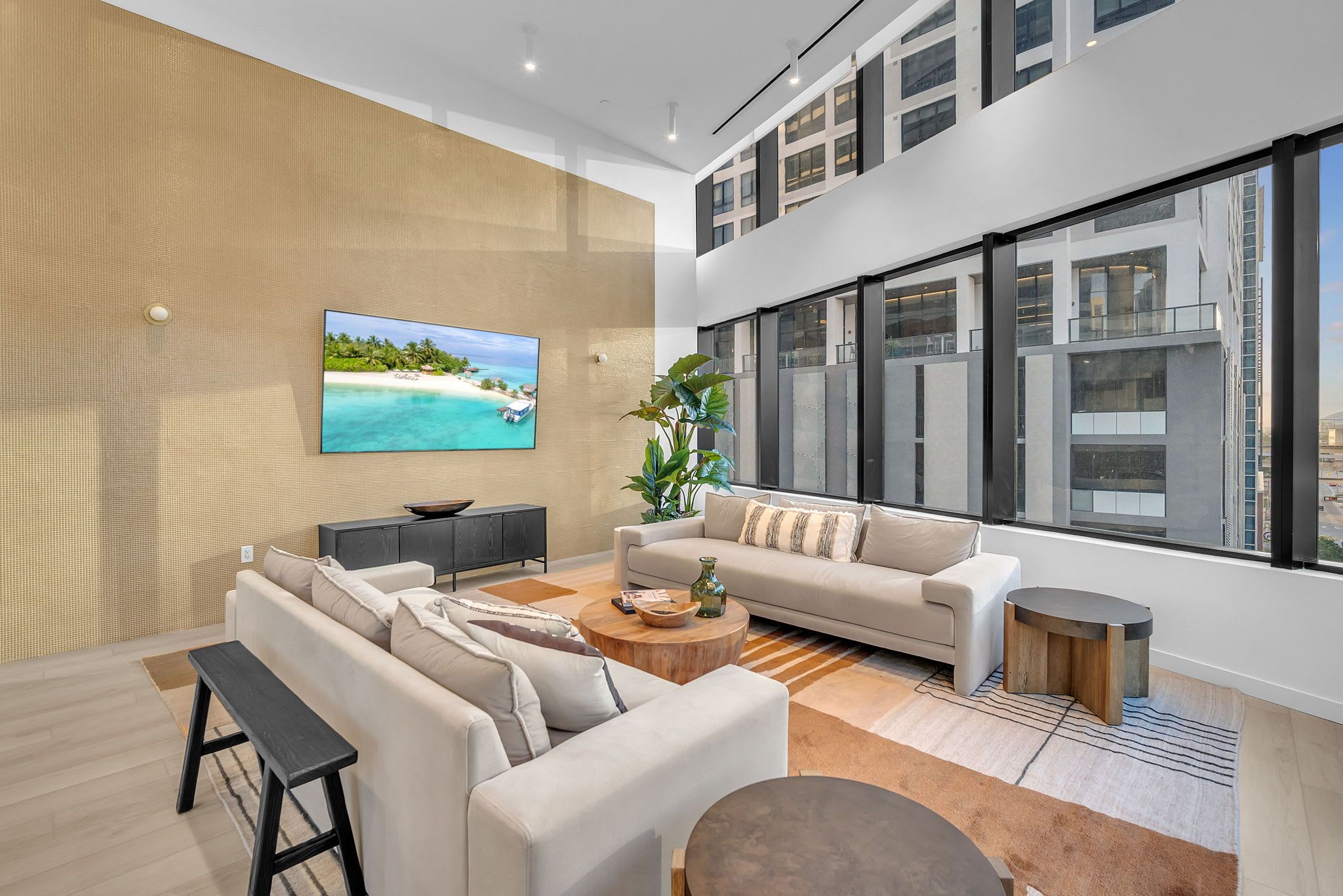 A modern living room with a large TV, a sofa, a coffee table, and a plant.