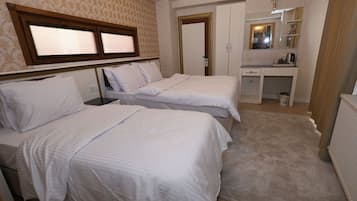 A hotel room with two beds, a desk with a mirror, and a radiator.