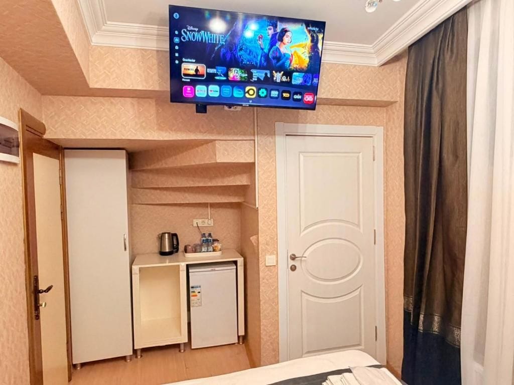 Une chambre d’hôtel équipée d’un téléviseur fixé au mur, d’une petite kitchenette avec un réfrigérateur, un four à micro-ondes et une machine à café.
