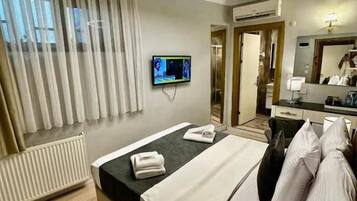 Ein Hotelzimmer mit einem Bett, einem Fernseher, einem Spiegel und einem Fenster mit Jalousien.