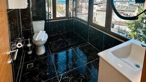 A modern bathroom with a toilet, sink, and shower area, featuring large windows and a view of the cityscape. - Leili Hagiya Sofiya Hotel (Fatih)