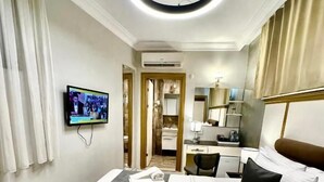 A hotel room with a bed, a television, a desk, and a bathroom visible through an open door. - Leili Hagiya Sofiya Hotel (Fatih)