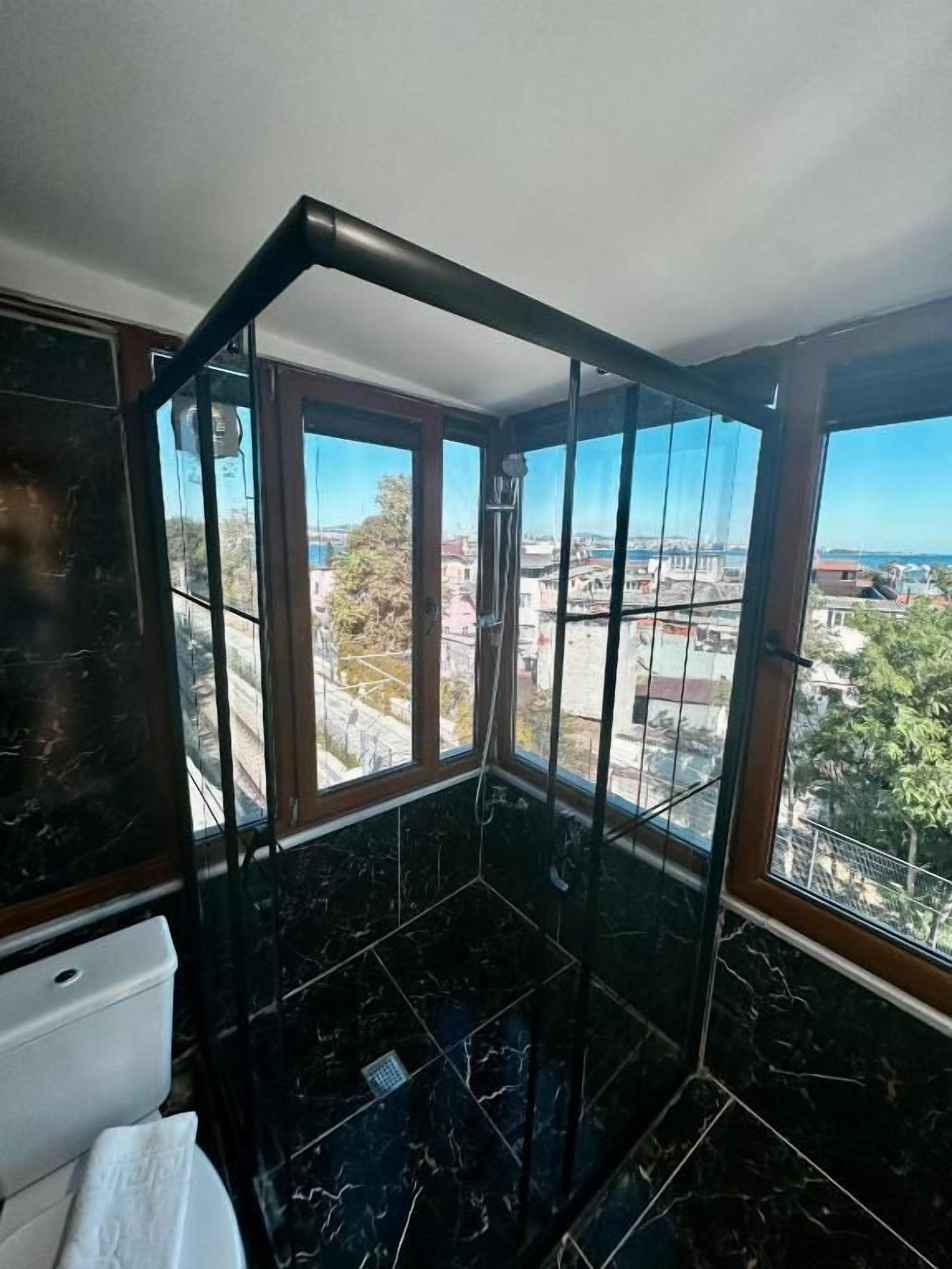 Ein Badezimmer mit Blick auf eine Stadtlandschaft durch große Fenster.