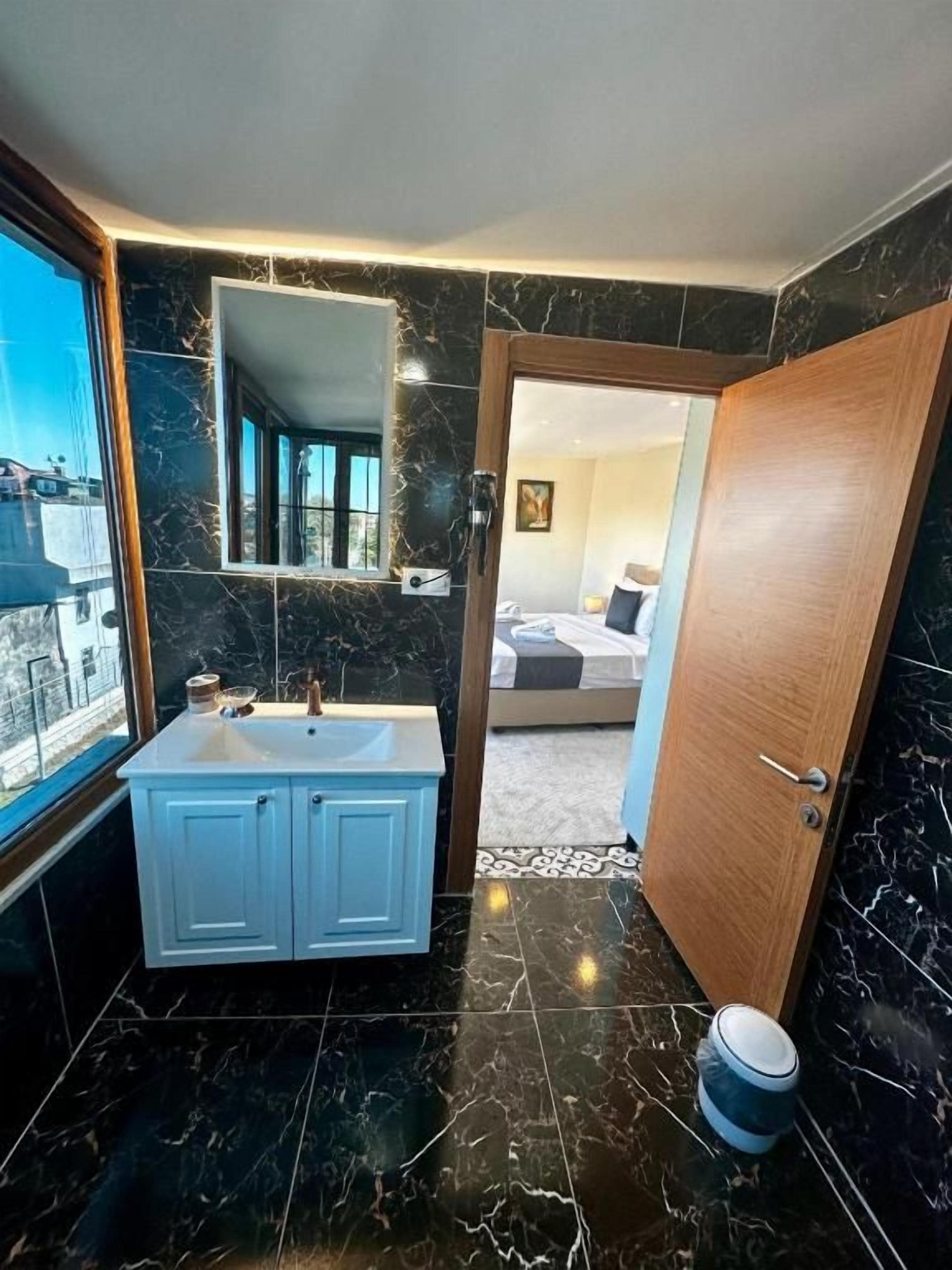 Ein modernes Badezimmer mit Marmorboden, einem Waschbecken mit Schränken und einem Spiegel.