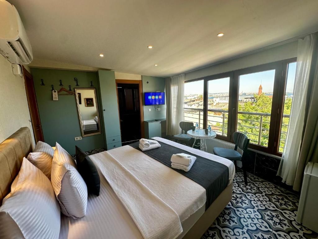 Ein Hotelzimmer mit Bett, Schreibtisch, Stuhl, Fernseher und einem Balkon mit Blick auf die Stadt.