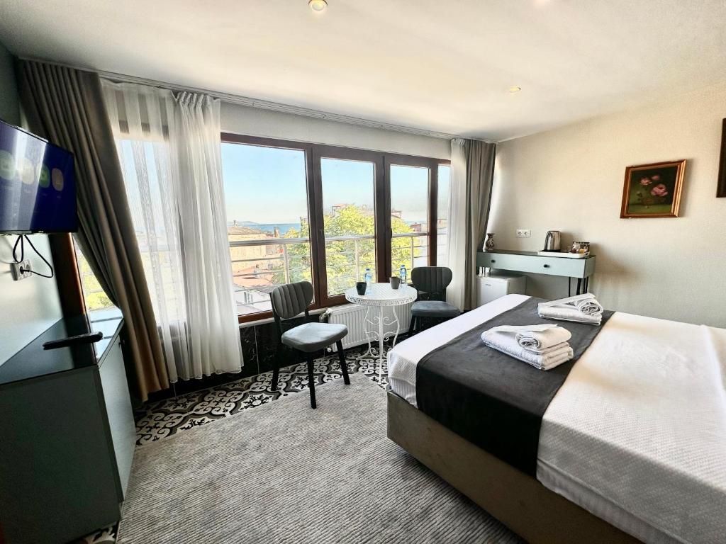 Une chambre d’hôtel équipée d’un lit, d’un bureau, d’une chaise, d’une petite table et d’un téléviseur.