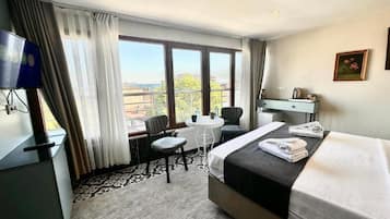 Une chambre d’hôtel équipée d’un lit, d’un bureau, d’une chaise, d’une petite table et d’un téléviseur.