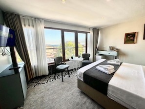 Habitación de hotel con cama, escritorio, silla, mesita y televisor.
