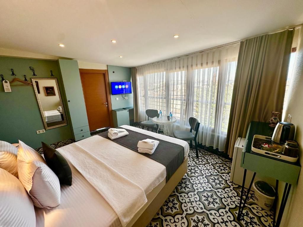 Ein Hotelzimmer mit Bett, Schreibtisch, Stuhl, Fernseher und einem Fenster mit Vorhängen.