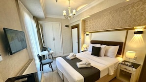 A hotel room with a bed, bedside table, lamp, and a television on a stand. - Leili Hagiya Sofiya Hotel (Fatih)