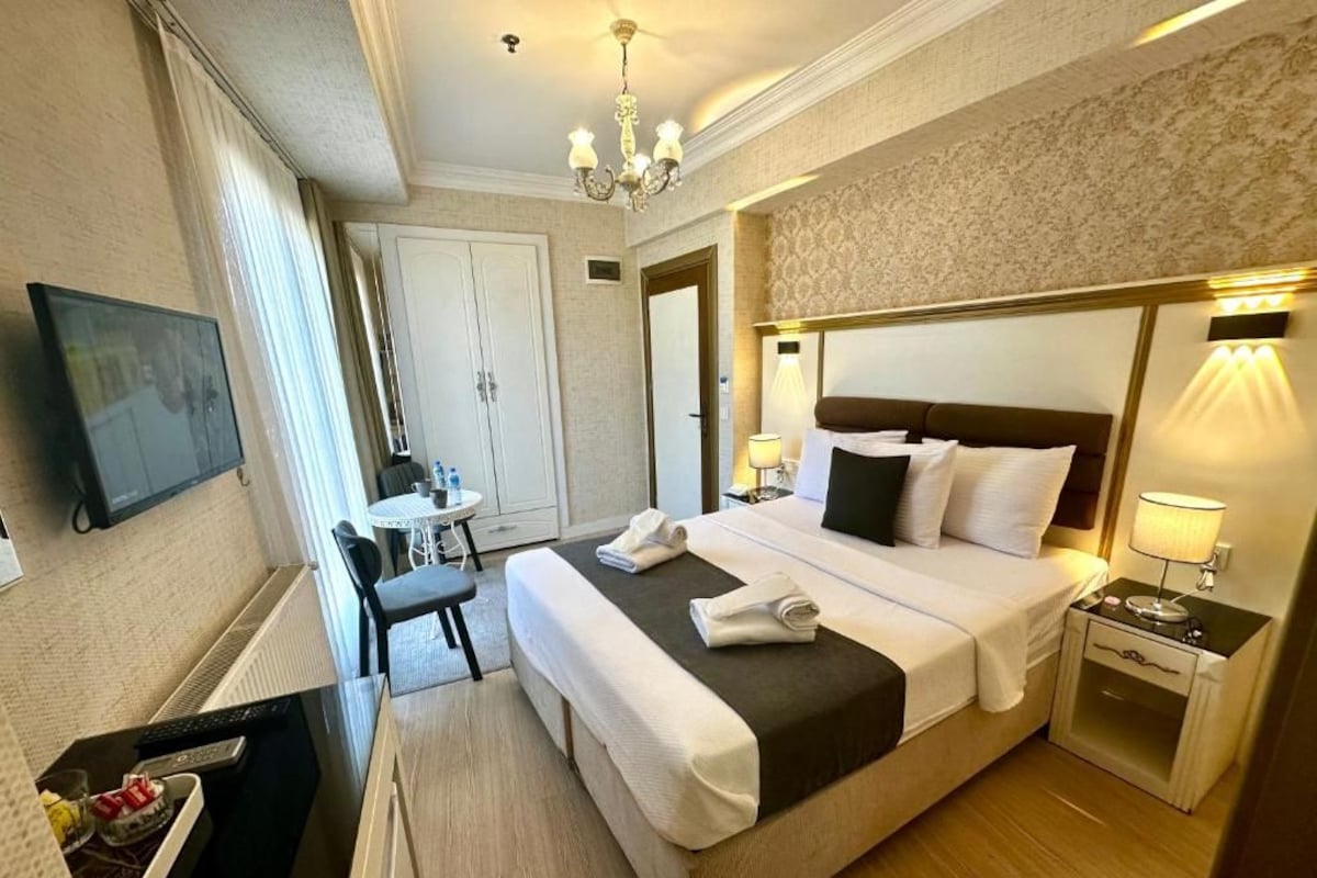 Ein Hotelzimmer mit einem Bett, einem Nachttisch, einer Lampe und einem Fernseher auf einem Beistelltisch.