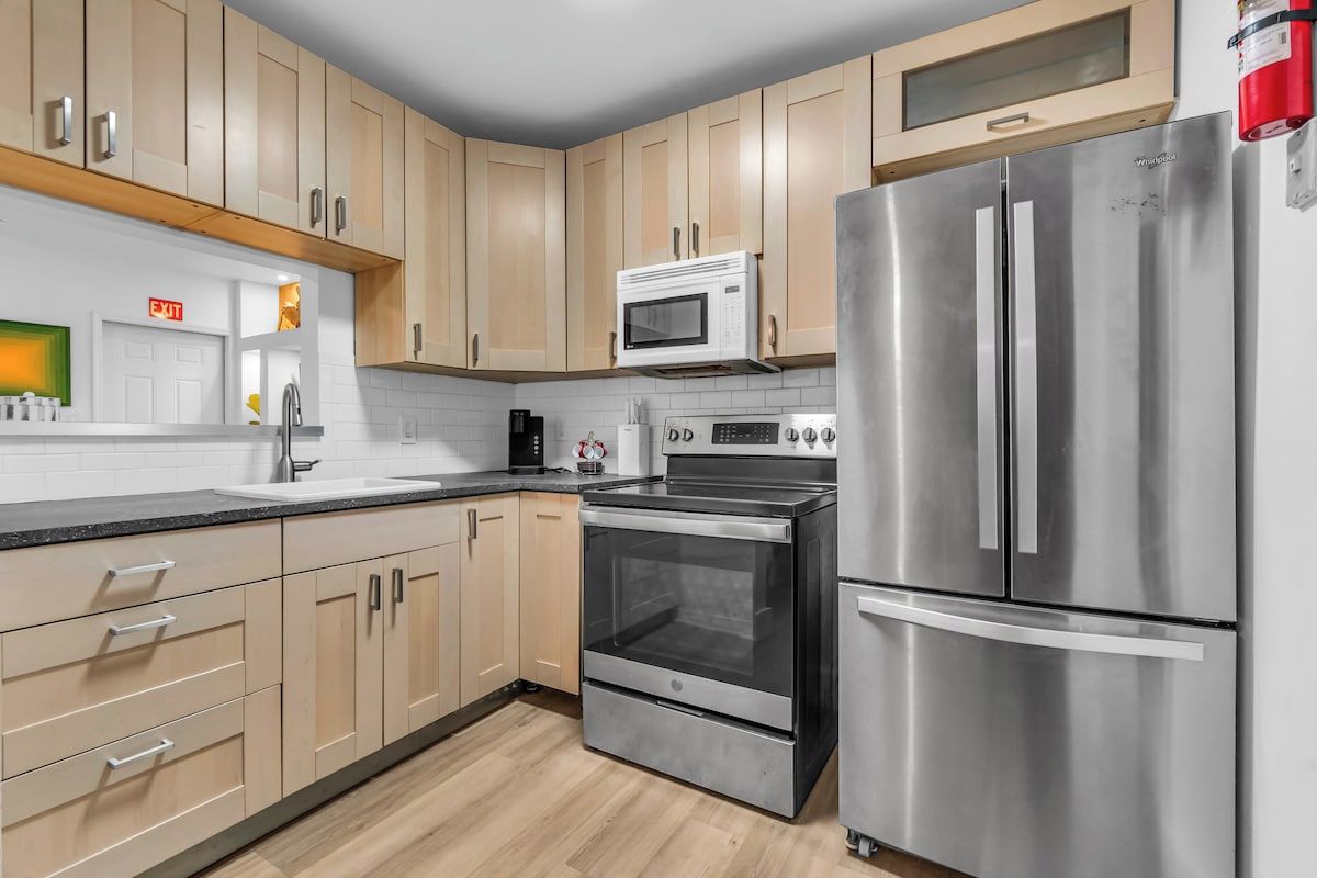 Una cocina moderna con electrodomésticos de acero inoxidable, armarios de madera y un microondas integrado.