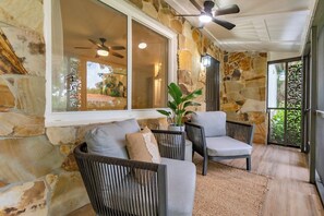 A stone-walled room with a ceiling fan, a large window, and a view of the outdoors. - Tropical Oasis - 3BR, 10 Min Bal Harbour- Parking (Biscayne Park)