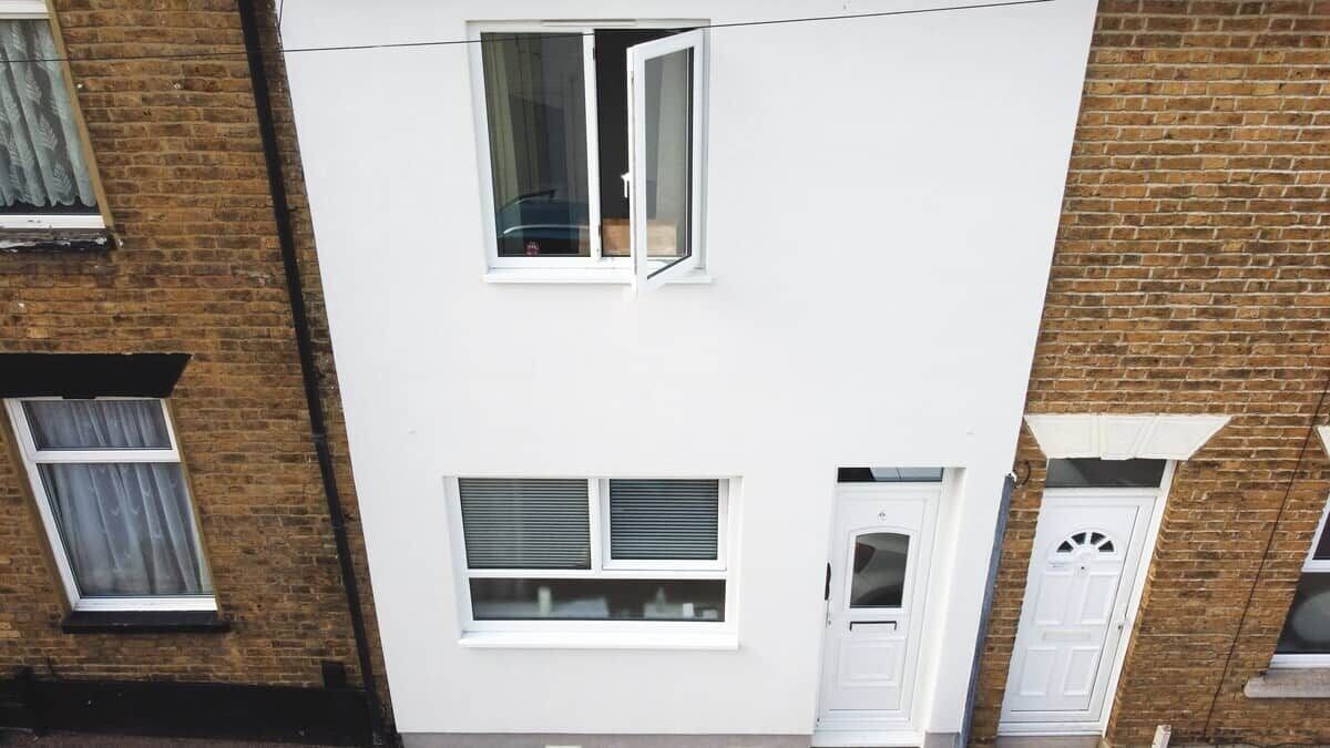 Un bâtiment à deux étages, doté d’une façade blanche, d’une fenêtre visible avec un rideau et d’une porte avec une petite fenêtre.