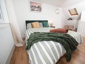 A bedroom with a bed, a nightstand, a lamp, a window with curtains, a framed picture on the wall, and a small table with a mirror. - Gorgeous 3 Bedroom House for Short-Medium Stays (Chatham)