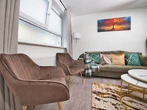 A living room with a sofa, two armchairs, a coffee table, and a painting on the wall. - Gorgeous 3 Bedroom House for Short-Medium Stays (Chatham)
