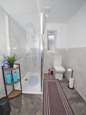 A modern bathroom with a glass-enclosed shower, a toilet, and a sink. - Gorgeous 3 Bedroom House for Short-Medium Stays (Chatham)