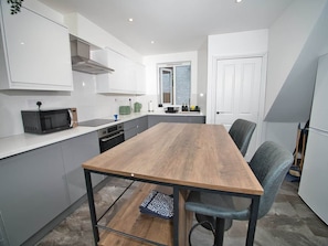 A modern kitchen with a wooden table, grey cabinets, and a microwave. - Gorgeous 3 Bedroom House for Short-Medium Stays (Chatham)
