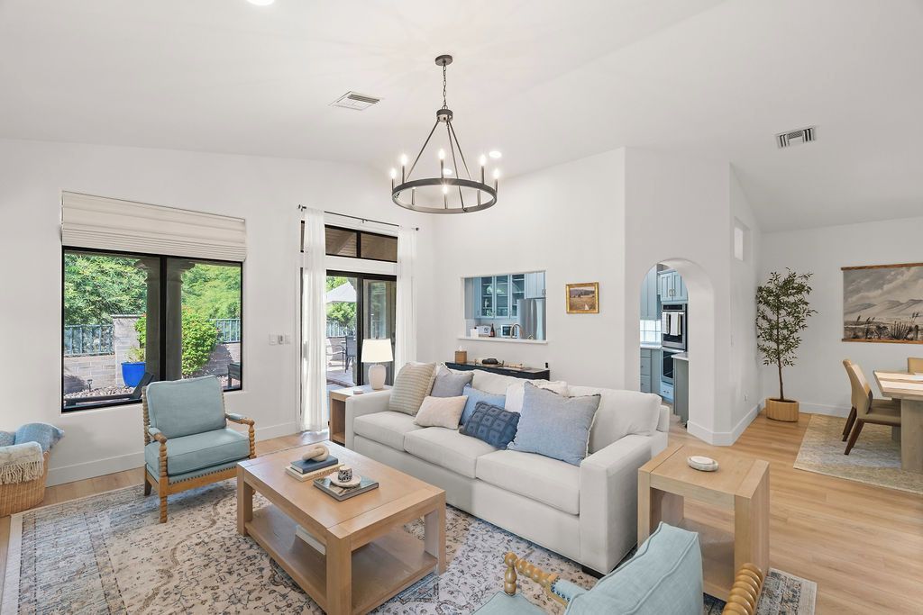 A modern living room with a sofa, armchairs, a coffee table, and a dining area with a table and chairs.