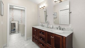A bathroom with a double vanity, a large mirror, and a light fixture above the mirror. - Newly Renovated Foothills Home at the Base of the Catalina Mountains (Tucson)