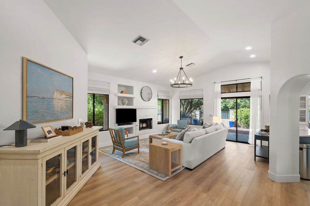 A spacious living area with a fireplace, a large window, and a modern chandelier.