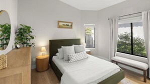 A bedroom with a bed, bedside table, lamp, window with curtains, and a view of greenery. - Newly Renovated Foothills Home at the Base of the Catalina Mountains (Tucson)