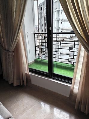 A room with a large window, curtains, a tiled floor, and a view of a building with balconies. - 1BHK with luxury amenities (Islamabad)