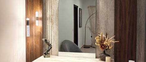 A bathroom with a wooden vanity, a large mirror, and a modern light fixture.