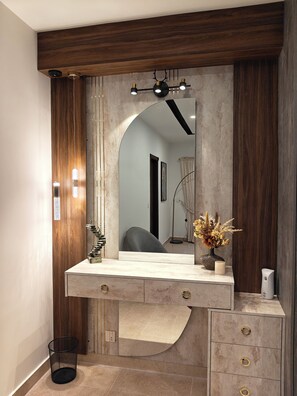 A bathroom with a wooden vanity, a large mirror, and a modern light fixture. - 1BHK with luxury amenities (Islamabad)