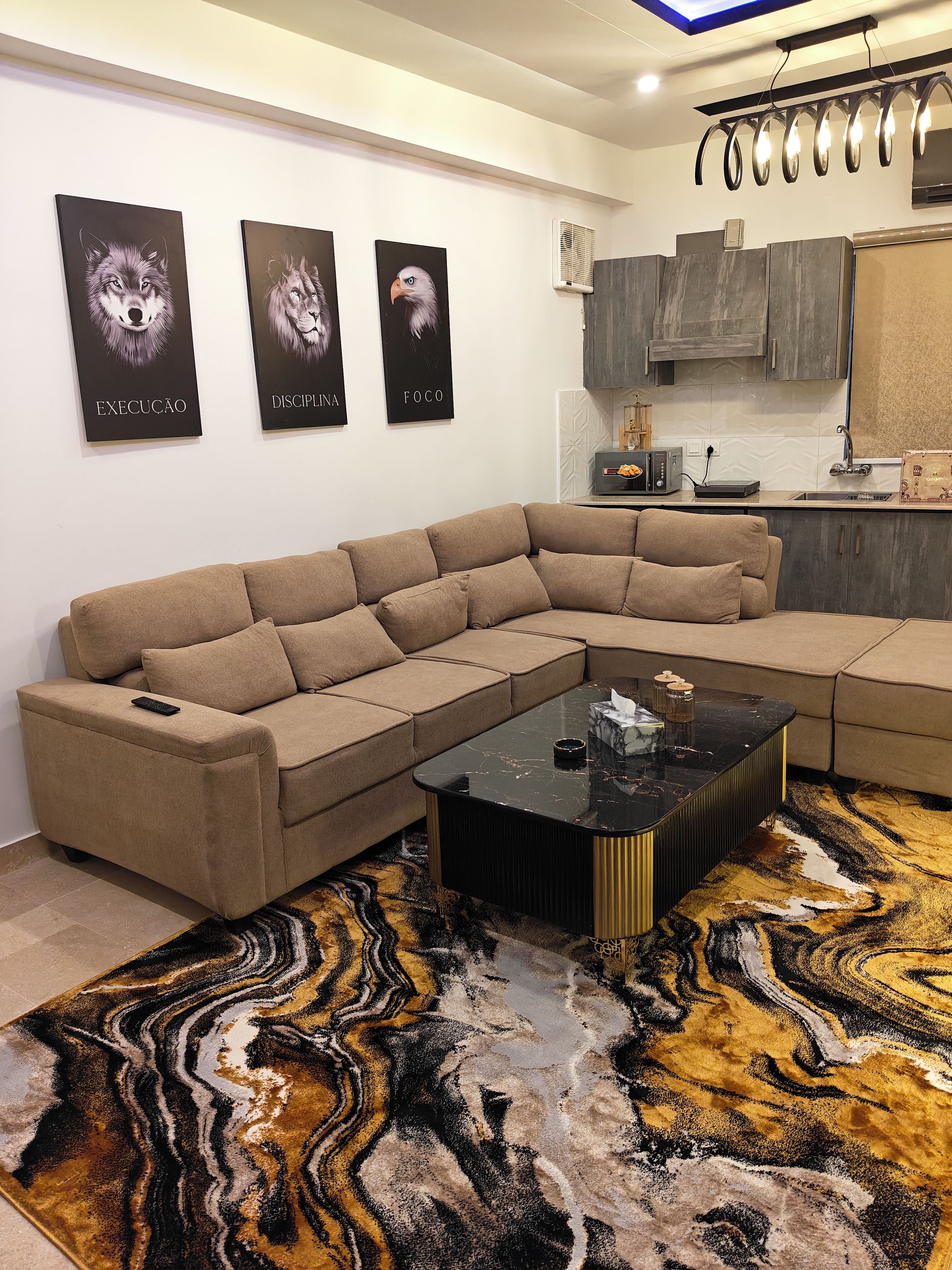A modern living room with a sectional sofa, a black coffee table, and a patterned rug.