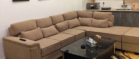 A modern living room with a sectional sofa, a black coffee table, and a patterned rug.