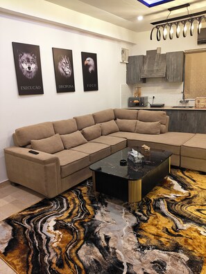 Una sala de estar moderna con un sofá modular, una mesa de centro negra y una alfombra estampada.