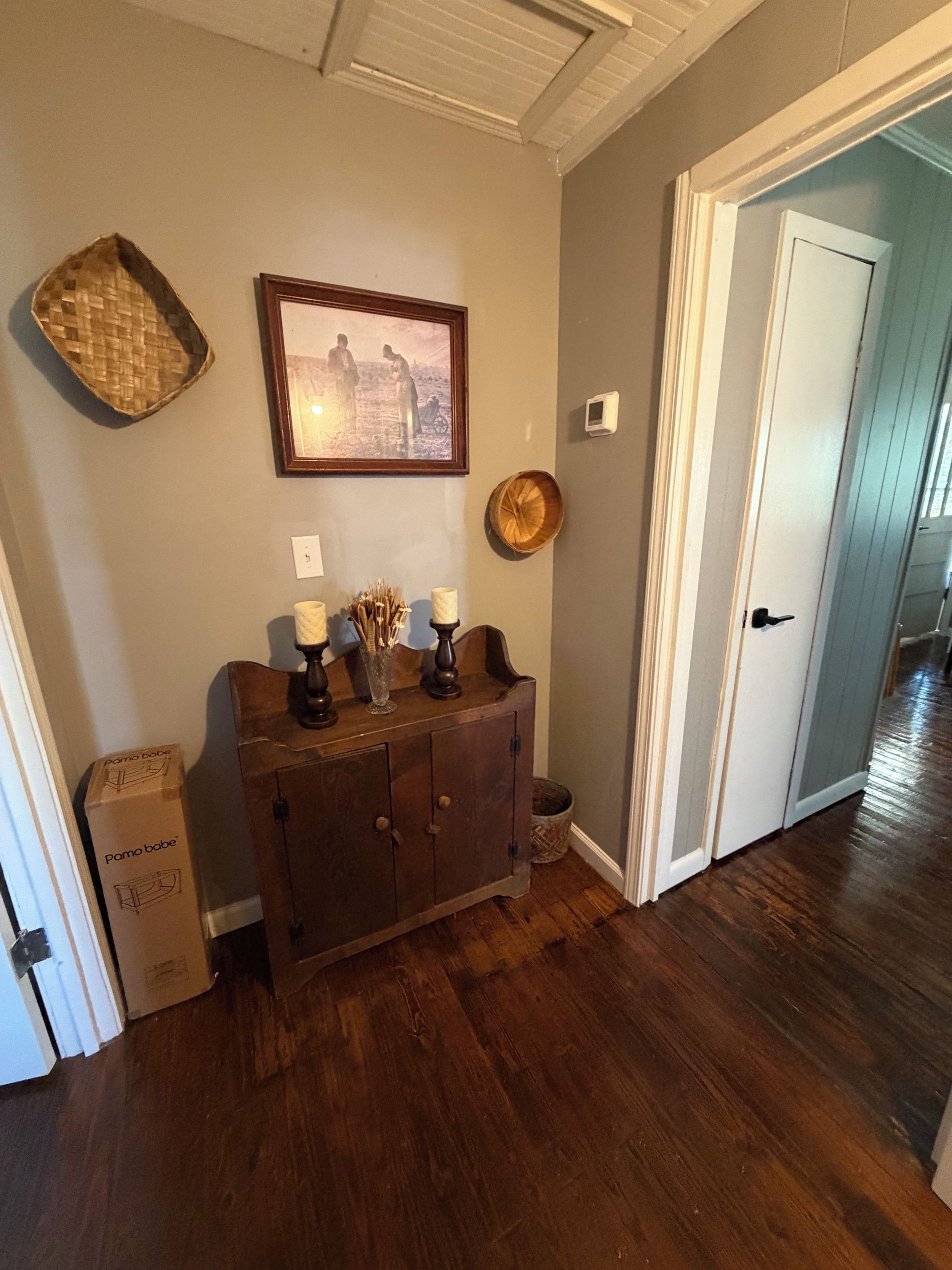 Un couloir avec une armoire en bois, un tableau encadré et une porte.