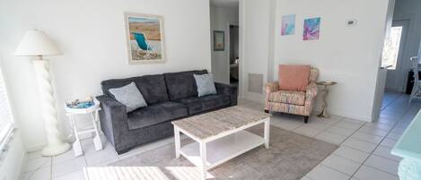 Una sala de estar con sofá, mesa de centro, lámpara y sillón.