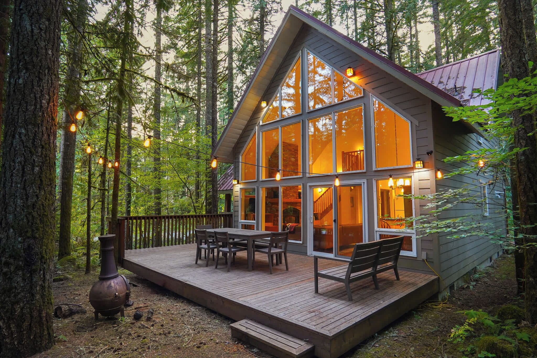 A cabin with a deck, large windows, and a staircase leading to the interior.